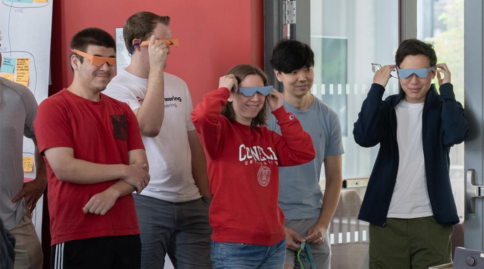 A group of five students are wearing construction-paper goggles for an exercise.