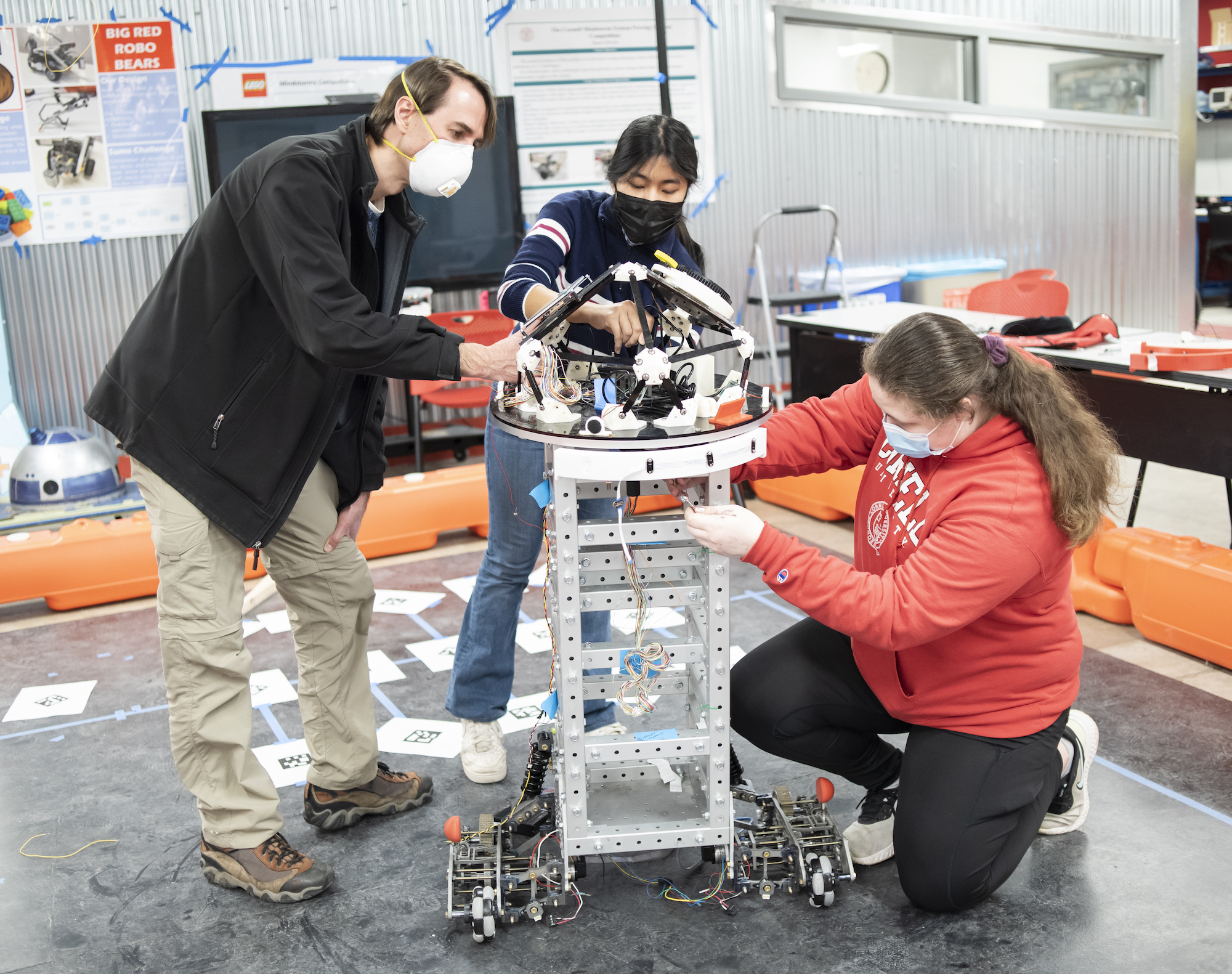 two students and professor work on a robot